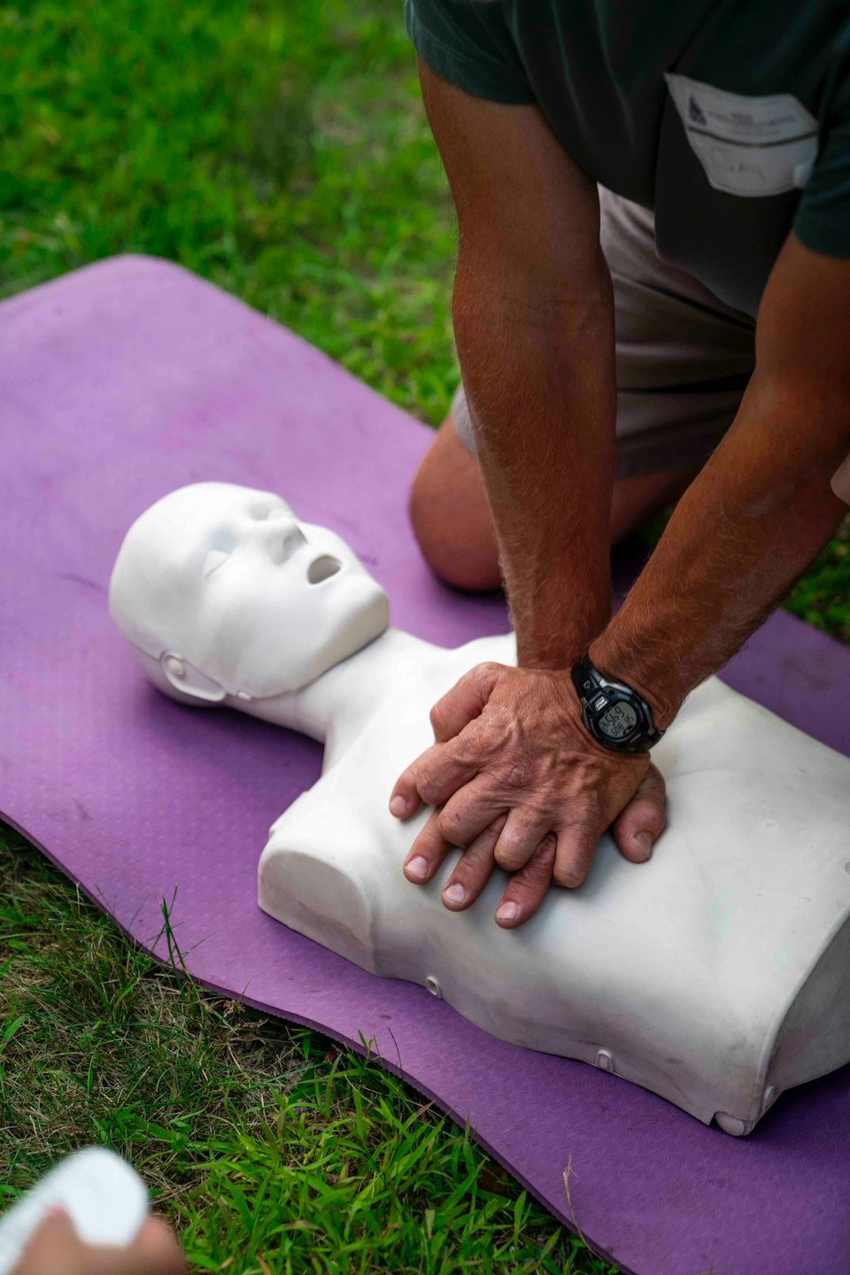 Person performing chest compressions on a CPR training mannequin.